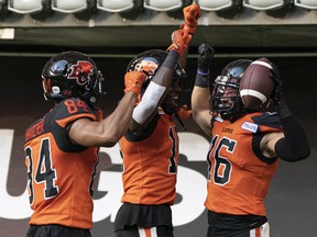 B.C. Lions' Bryan Burnham, right, celebrates with teammates Keon Hatcher, left, and Dominique Rhymes after scoring a touchdown against the Toronto Argonauts during CFL action in Vancouver on June 25.