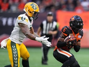 B.C. Lions' T.J. Lee, right, intercepts a pass intended for Edmonton Elks' Jalin Marshall during the first half of CFL football game in Vancouver, on Saturday, June 11, 2022.