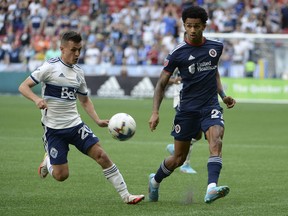 Vancouver Whitecaps midfielder Andres Cubas (20) challenges New England Revolution midfielder Dylan Borrero (27) during the first half at B.C. Place on Sunday.