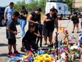 Community members pay their respects at a memorial set up for the migrants who were found dead inside a trailer truck in San Antonio, Texas, on June 30, 2022.