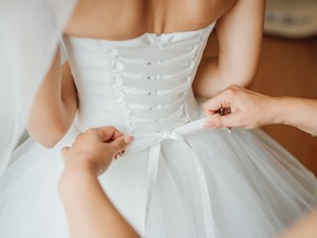 Bridesmaid makes bow-knot on the back of brides wedding dress