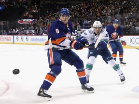 New York Islanders defenceman Noah Dobson (left) defends against then-Canuck Adam Gaudette in a February 2020 NHL game in New York.