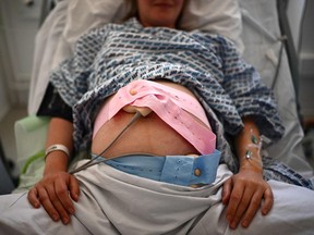 A pregnant woman lies on her bed with monitoring devices placed on her belly at a maternity ward of a hospital.