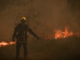 A firefighter waves to colleagues during an operation to try to control a forest fire near Louchats,, as wildfires continue to spread in the Gironde region of southwestern France on July 18, 2022.