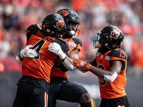 B.C. Lions' Keon Hatcher, from left to right, Jevon Cottoy and Dominique Rhymes celebrate Cottoy's touchdown against the Hamilton Tiger-Cats during the first half of CFL football game in Vancouver, on Thursday.