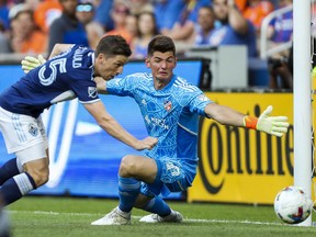 FC Cincinnati goalkeeper Roman Celentano (18) attempts to make a save while Vancouver Whitecaps midfielder Ryan Gauld (25) scores a goal in the first half at TQL Stadium.