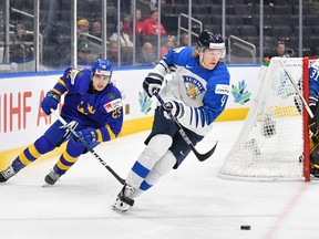Joni Jurmo #4 of Finland skates with the puck while being pursued by Liam Ohgren #25 of Sweden in the IIHF World Junior Championship on August 19, 2022 at Rogers Place in Edmonton, Alberta, Canada