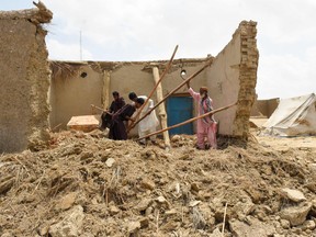 Local residents clear debris from their damaged house at a flood affected town called Gandawah in Jhal Magsi district, southwestern province of Balochistan, Pakistan on August 2, 2022.
