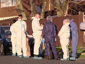 Police and forensic investigators gather at the scene where suitcases with the remains of two children were found, after a family, who are not connected to the deaths, bought them at an online auction for an unclaimed locker, in Auckland, New Zealand, Aug. 11, 2022 in this still image taken from video.