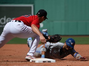 Toronto Blue Jays designated hitter Lourdes Gurriel Jr. slides safely back to first ahead of the tag by Boston Red Sox first baseman Bobby Dalbec during a July 24, 2022 American League game at Fenway Park in Boston.