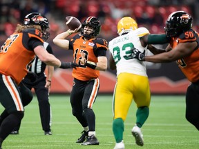 B.C. Lions quarterback Nathan Rourke (12) passes as Phillip Norman (50) holds off Edmonton Elks’ Kwaku Boateng (93) during the first half of a CFL football game in Vancouver, on Friday, November 19, 2021.