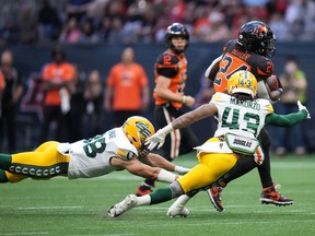B.C. Lions’ James Butler (24) avoids tackles by Edmonton Elks’ Adam Konar, left, and Enock Makonzo (43) and runs for his second touchdown during the first half of CFL football game in Vancouver, on Saturday, June 11, 2022.