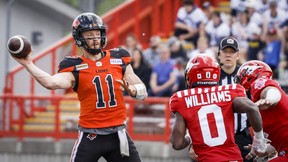 BC Lions quarterback Michael O'Connor, left, kicks the ball as Calgary Stampeders' Darius Williams closes in during first half preseason football action from the CFL in Calgary, Alberta on Saturday, May 28, 2022.