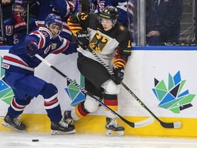 Američan Jacob Truscott (17) a Nemec Haakon Hanelt (19) zápasia o kotúč počas prvej tretiny majstrovstiev sveta IIHF v hokeji juniorov v Edmontone v utorok 9. augusta 2022.