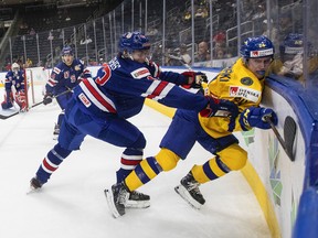 Američan Luke Hughes (43) kontroluje v nedeľu 14. augusta 2022 Švéda Jonathana Likrimackiho (24) počas prvej tretiny majstrovstiev sveta IIHF v hokeji juniorov v Edmontone.