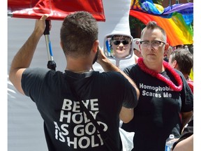 Dani Murphy, right, holds up a mirror with the words 'this is what hate looks like' to an anti-gay protester during the annual Gay Pride Parade in London, Ont. in 2017.