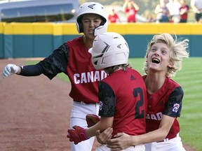 Canada's Ellis St. James (2) is greeted by teammates Benjamin Dartnell, left, and Lucas Fabbro, right, after driving in a run with a sacrifice bunt against Japan during the sixth inning of a baseball game at the Little League World Series tournament in South Williamsport, Pa., Friday, Aug. 19, 2022.