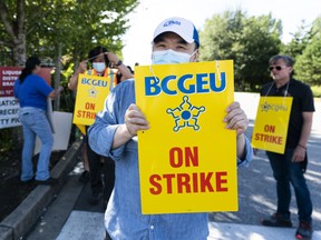 B.C. General Employees' Union (BCGEU) public service worker holds up a picket sign after walking off the job at a B.C. Liquor Distribution Branch wholesale and distribution centre in Delta this week.