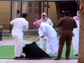 A woman (in black) is beaten by a group of men in Khamis Mushait, Saudi Arabia.