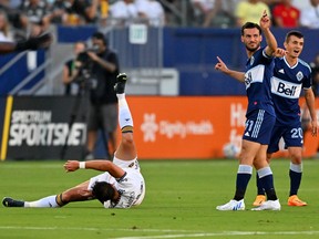 Aug 13, 2022; Carson, California, USA; Los Angeles Galaxy forward Javier Hernández (14) is upended by Vancouver Whitecaps defender Matteo Campagna (61) and midfielder Andrés Cubas (20) in the first half at Dignity Health Sports Park.