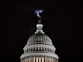 The moon is seen behind the dome of the U.S. Capitol building at night in Washington, D.C, Feb. 16, 2022.