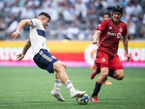 Vancouver Whitecaps' Lucas Cavallini, left, stumbles as he controls the ball in front of Toronto FC's Shane O'Neill during the first half of the Canadian Championship soccer final, in Vancouver, on Tuesday, July 26, 2022.