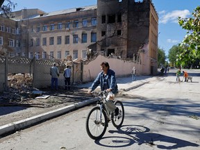 A man rides a bicycle past the ruins of a building destroyed by recent shelling in Kadiivka in Luhansk region, Ukraine. Luhansk is one of four regions that Russia plans to hold a referendum on joining the Russian Federation. The referendums are being called a "sham" by Ukraine and Western governments.