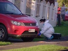 An investigator works at the scene where suitcases with the remains of two children were found, after a family, who are not connected to the deaths, bought them at an online auction for an unclaimed locker, in Auckland, New Zealand, Aug. 11, 2022 in this still image taken from video.