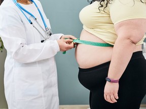 Obesity, unhealthy weight. Nutritionist inspecting a woman's waist using a meter tape to prescribe a weight loss diet