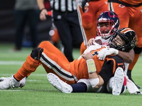 BC Lions quarterback Mike Riley, 13, hovers over Woody Barron of the Montreal Alouettes after rushing for a first down in the second half of a CFL football game in Vancouver, Saturday, Sept. 28, 2019. lying down