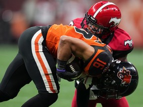 Lions receiver Bryan Burnham is wrapped up by Calgary’s Brad Muhammad on Saturday at B.C. Place Stadium.
