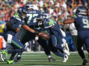 Geno Smith #7 of the Seattle Seahawks looks to hand off to Kenneth Walker III #9 of the Seattle Seahawks against the Arizona Cardinals during the first half at Lumen Field on October 16, 2022 in Seattle, Washington.