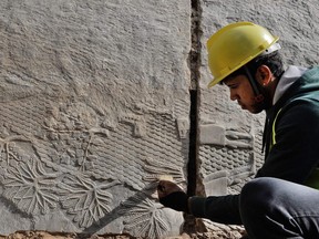 An Iraqi worker excavates a rock-carving relief recently found at the Mashki Gate, one of the monumental gates to the ancient Assyrian city of Nineveh, on the outskirts of what is today the northern Iraqi city of Mosul on October 19, 2022.