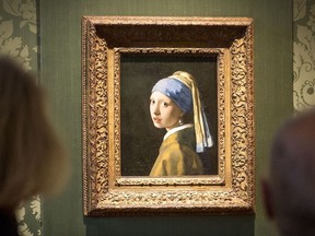 Visitors looks at the Johannes Vermeer's painting "Girl with a Pearl Earring" at the Mauritshuis museum in The Hague, 27 October 2022. - Dutch police arrested three people after climate activists targeted Johannes Vermeer's painting "Girl with a Pearl Earring". (Photo by LEX VAN LIESHOUT/ANP/AFP via Getty Images)