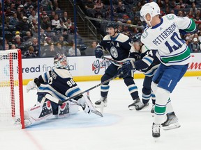 Vancouver Canucks' Elias Pettersson, right, scores a goal against Columbus Blue Jackets' Elvis Merzlikins during the first period of an NHL hockey game Tuesday, Oct. 18, 2022, in Columbus, Ohio.