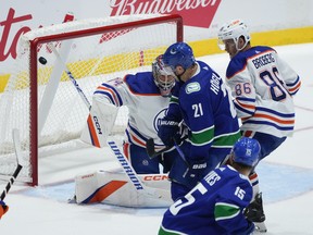 Vancouver Canucks' Nils Hoglander (21), looks for the puck before scoring against Edmonton Oilers goalie Stuart Skinner (74) during the first period of a pre-season NHL hockey game in Abbotsford, B.C., on Wednesday, October 5, 2022.