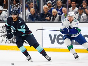 Oct 1, 2022; Seattle, Washington, USA; Seattle Kraken center Matty Beniers (10) skates with the puck ahead of Vancouver Canucks left wing Tanner Pearson (70) during the second period at Climate Pledge Arena. Mandatory Credit: Joe Nicholson-USA TODAY Sports