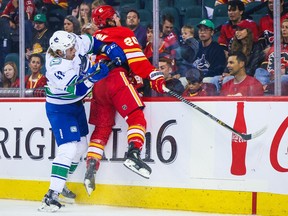 Canucks defenceman Noah Juulsen checks Calgary Flames centre Blake Coleman into the boards during the first period of their Sept. 25, 2002, pre-season game at the Scotiabank Saddledome.