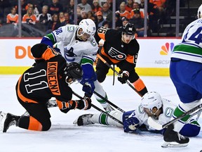 Philadelphia Flyers right wing Travis Konecny (11) reaches in as Vancouver Canucks defenceman Luke Schenn (2) covers the puck in the first period at Wells Fargo Center. Photo: Kyle Ross-USA Today Sports