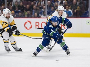 Pittsburgh Penguins forward Jeff Carter (77) watches Vancouver Canucks forward Conor Garland (8) make a pass in the first period at Rogers Arena Oct. 28.