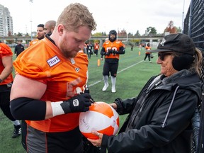 B.C. Lions fan Beckie Torra gathers a signature from offensive lineman Andrew Peirson following team practice at the Surrey.