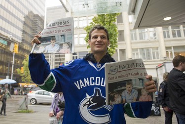 Vancouver Canucks Kevin Bieksa holds up copies of the Vancouver Sun during Raise a Reader Day in downtown Vancouver, BC, September, 24, 2014. (Richard Lam/PNG)