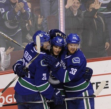 Vancouver Canucks Alex Edler 23, (left) celebrate  Kevin Bieksa's 3 (centre) goal with captain Henrik Sedin 33,  (r) during  first period action in  the Arizona Coyotes in Rogers Arena in Vancouver on December 22, 2014.  Mark van Manen/PNG