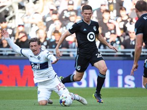 Vancouver Whitecaps midfielder Ryan Gauld (25) and Minnesota United midfielder Will Trapp (20) fight for the ball during the first half at Allianz Field.