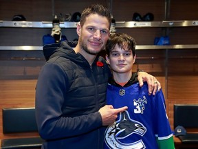 Former Vancouver Canuck Kevin Beeksa stands with his son Cole in the Canucks locker room before the NHL game against the Anaheim Ducks at Rogers Arena Nov. 3, 2022.