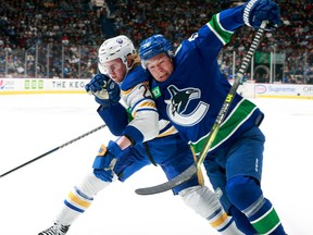 Rasmus Darling of the Buffalo Sabers checks out Curtis Lazar of the Vancouver Canucks during an NHL game at Rogers Arena on October 22, 2022.