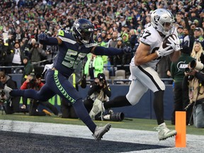 Foster Moreau of the Las Vegas Raiders scores a touchdown past Jordyn Brooks of the Seattle Seahawks in the fourth quarter at Lumen Field on November 27, 2022 in Seattle, Washington.