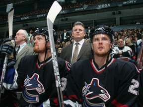 Then-head coach Marc Crawford stands between the Sedin twins on the Canucks’ bench during a December 2005 NHL game at Rogers Arena. Crawford gives their journeyman linemate Trent Klatt for ‘clearing space for them’ as they developed into stars.