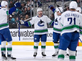 Vancouver Canucks defenceman Kyle Burroughs, centre, celebrates with teammates after scoring a goal against the San Jose Sharks during the first period of an NHL hockey game, Sunday, Nov. 27, 2022, in San Jose, Calif.