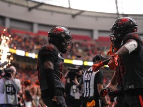 B.C. Lions' Alexander Hollins (13) and Dominique Rhymes (19) celebrate Hollins' touchdown against the Calgary Stampeders during first half CFL Western semi-final football action in Vancouver on Sunday November 6, 2022.